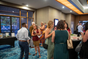 Colorful indoor networking event with diverse attendees, drinks, and booths at Toms Photo Gallery.